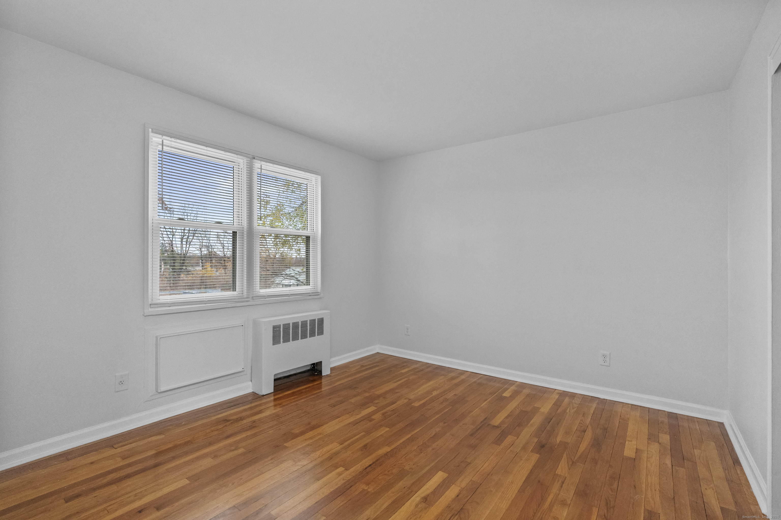 56 Blachley Road, Unit B Stamford, CT 06902 - Photo 12 of 26 a view of an empty room with wooden floor and a window