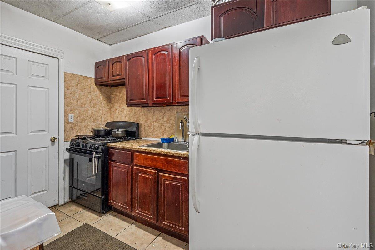 89-21 129th Street Queens, NY 11418 - Photo 11 of 19 a kitchen with stainless steel appliances granite countertop a refrigerator and a stove