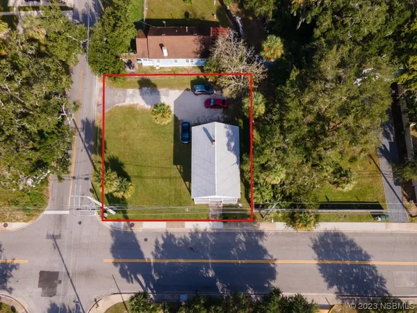 an aerial view of a house with a yard and a large tree