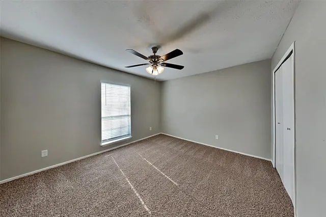 an empty room with windows and ceiling fan