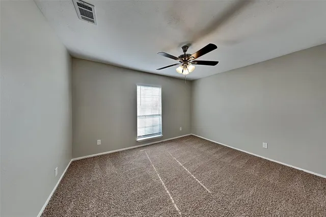 an empty room with windows and ceiling fan