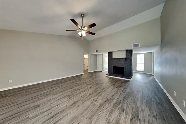 an empty room with wooden floor fireplace and a window