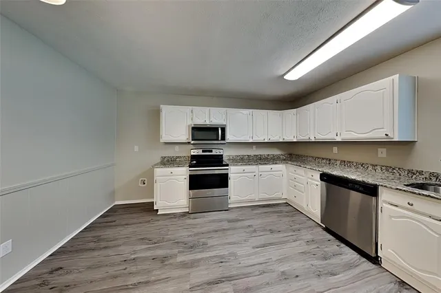 a kitchen with granite countertop white cabinets and white appliances