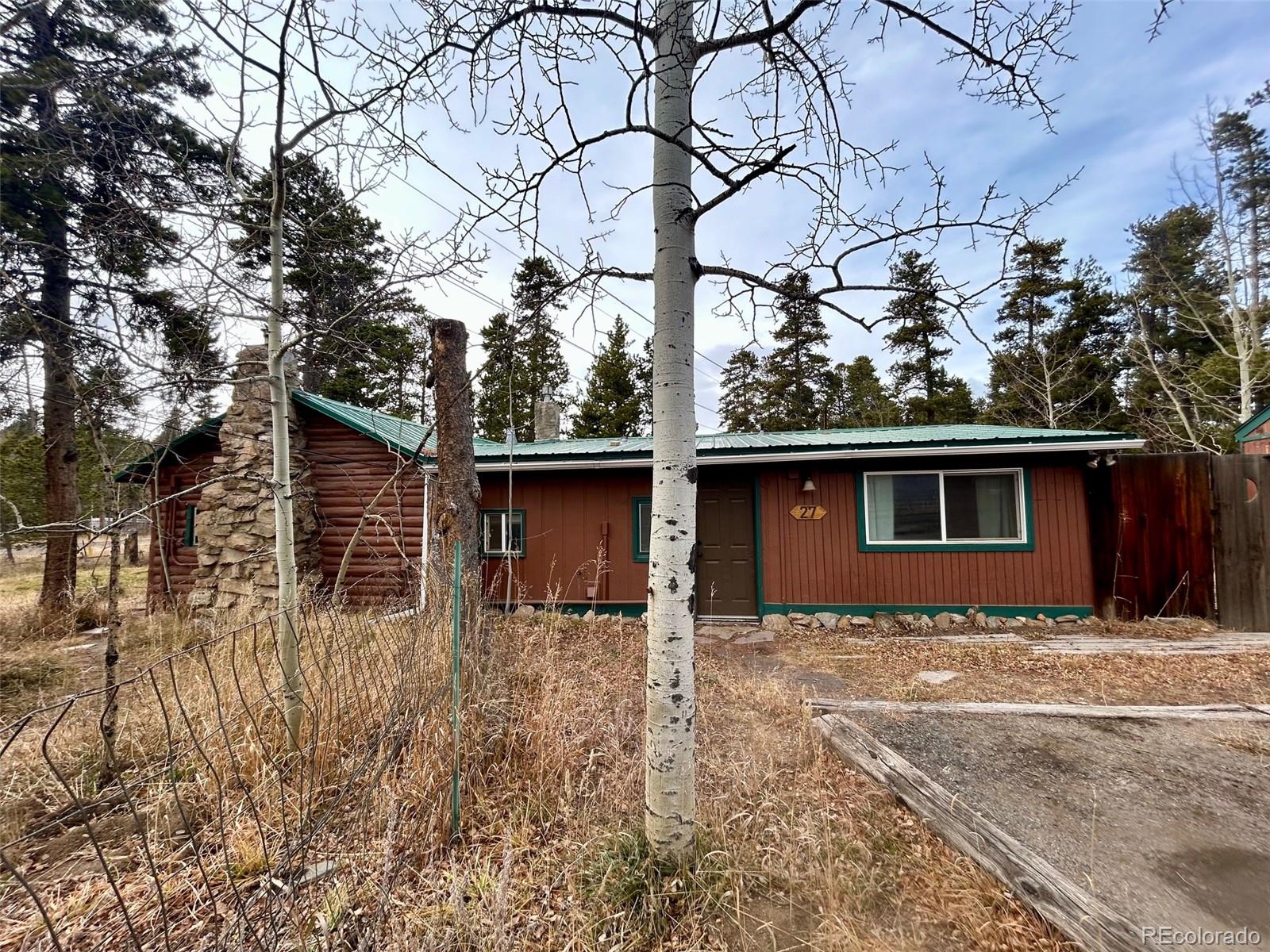 a backyard of a house with large trees and wooden fence