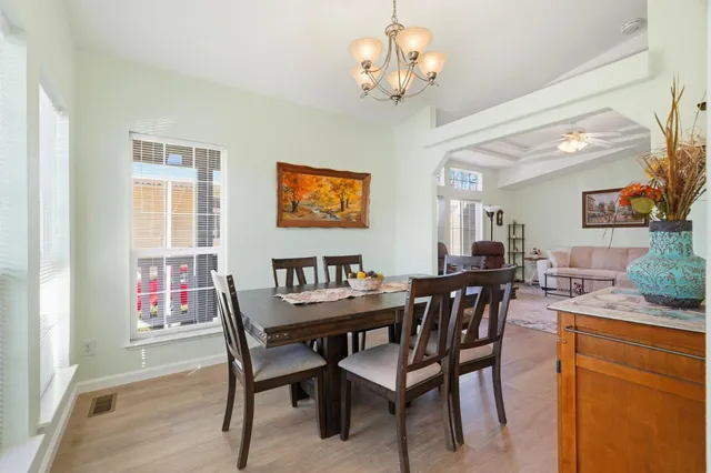a view of a dining room with furniture a chandelier and wooden floor