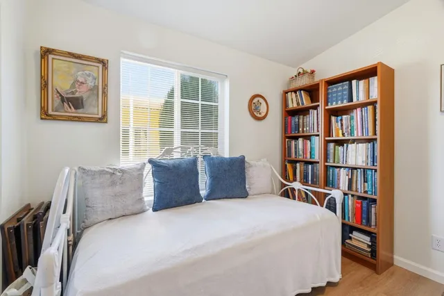 a bedroom with a bed a book shelf and a window