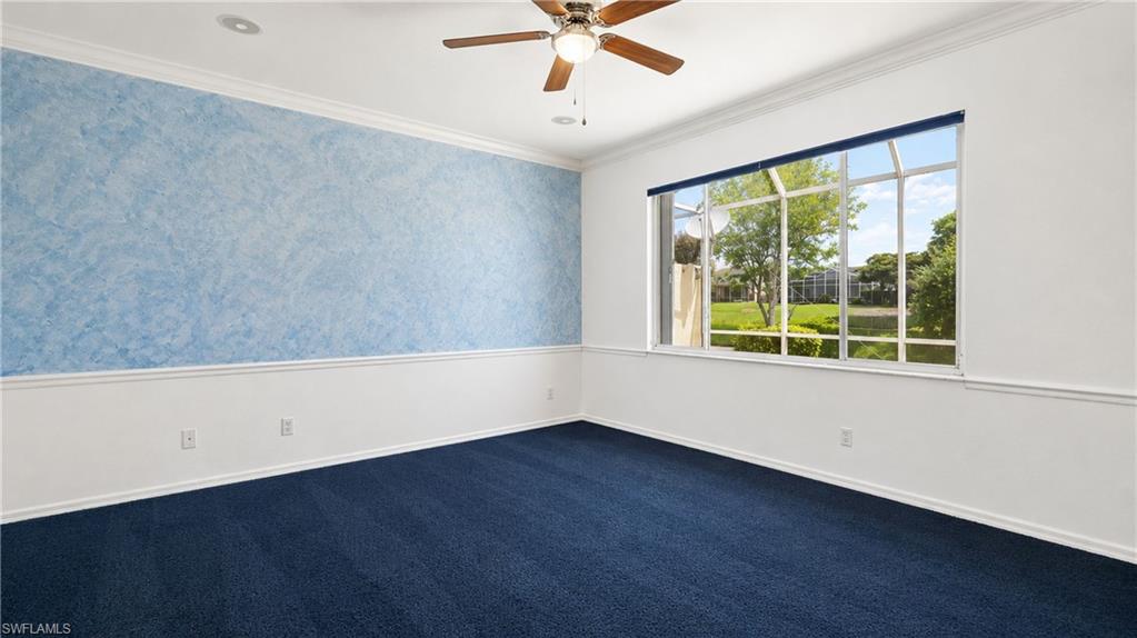 7737 Haverhill Court Naples, FL 34104 - Photo 16 of 37 Room featuring a broad window with a green outdoor scenery, ceiling fan, crown molding, and two-tone wall treatment with a blue accent