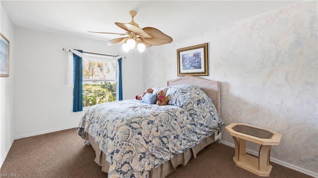 7737 Haverhill Court Naples, FL 34104 - Photo 20 of 37 Carpeted bedroom featuring a large window, a ceiling fan with integrated lighting, white baseboards, and a textured accent wall