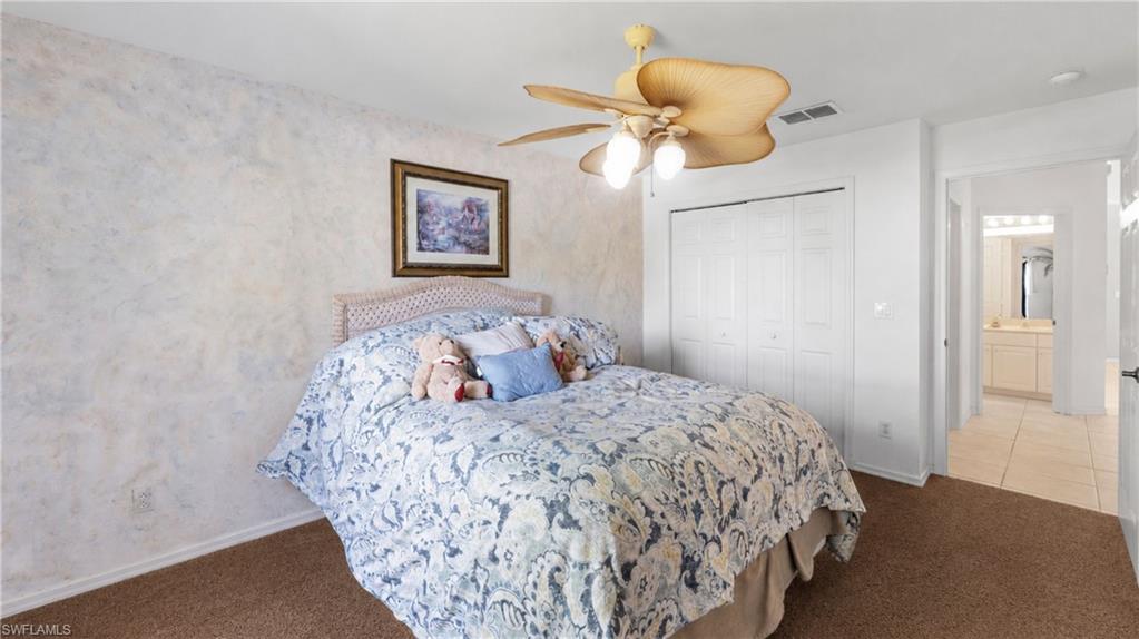 7737 Haverhill Court Naples, FL 34104 - Photo 21 of 37 Bedroom featuring textured wall finish, ceiling fan with integrated lighting, brown carpet flooring, and bi-fold closet doors