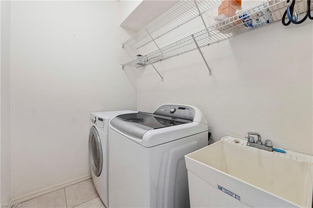7737 Haverhill Court Naples, FL 34104 - Photo 25 of 37 Dedicated laundry space featuring a utility sink, wall-mounted wire shelving, and tile flooring