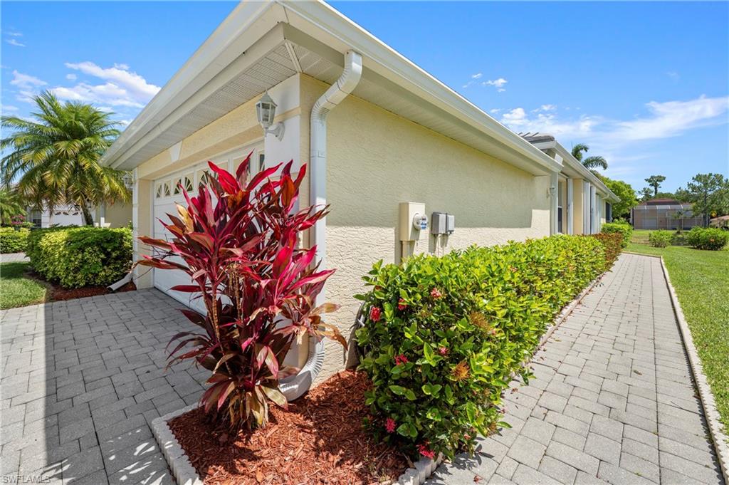 7737 Haverhill Court Naples, FL 34104 - Photo 3 of 37 Exterior featuring stucco siding, a white garage door with decorative windows, and a paver driveway