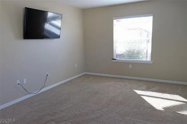 a view of an empty room with a window and a flat screen tv