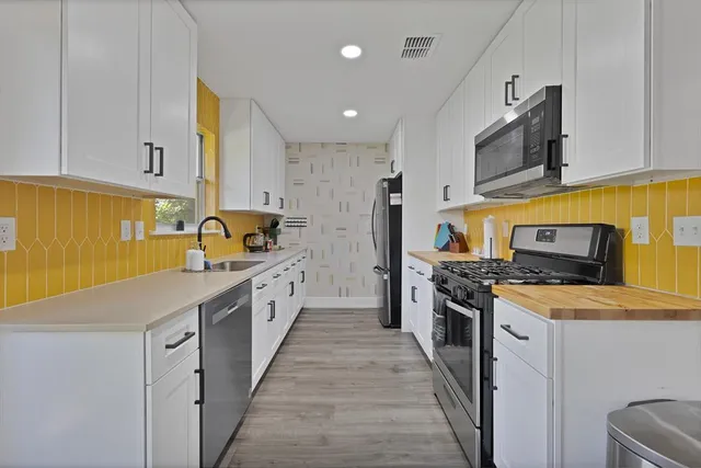 a large kitchen with stainless steel appliances granite countertop a stove a sink and a refrigerator