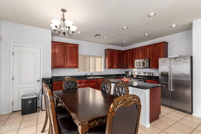 a kitchen with stainless steel appliances a table and chairs in it