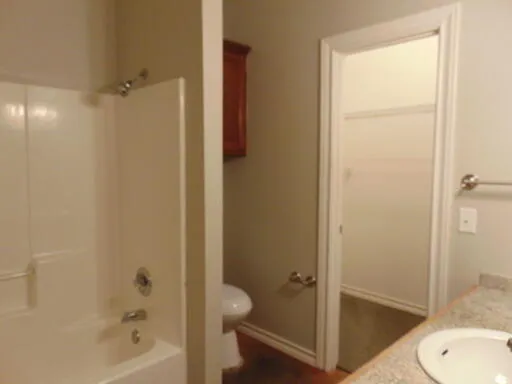 a bathroom with a granite countertop bathtub shower and toilet