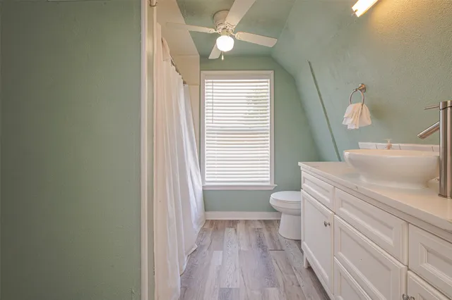a bathroom with a toilet a sink and wooden floor