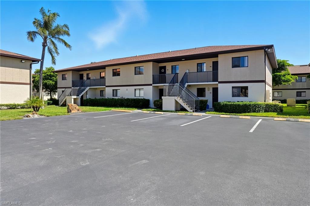 4790 South Cleveland Avenue, Unit 907 Fort Myers, FL 33907 - Photo 1 of 24 View of building exterior featuring stairs and uncovered parking