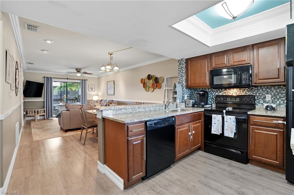 4790 South Cleveland Avenue, Unit 907 Fort Myers, FL 33907 - Photo 11 of 24 Kitchen featuring crown molding, tile backsplash, black appliances, and granite counters and peninsula