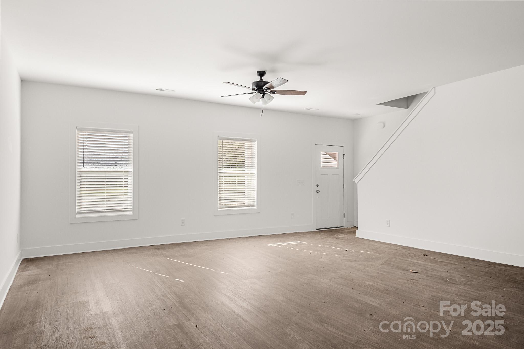 3303 Old Pageland Monroe Road Monroe, NC 28112 - Photo 2 of 37 an empty room with wooden floor ceiling fan and windows