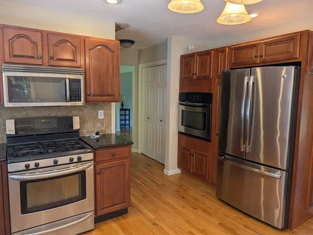 a kitchen with granite countertop a refrigerator stove and microwave