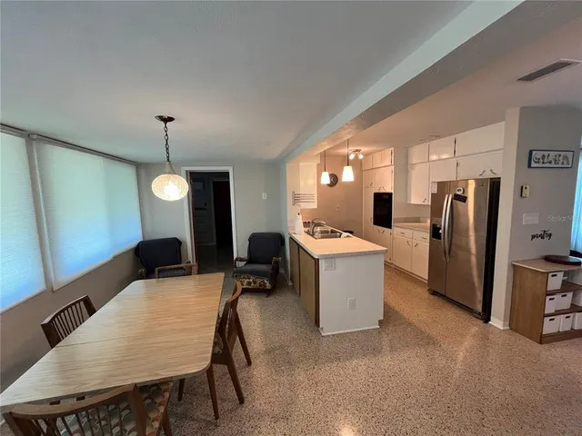 a large kitchen with a table chairs refrigerator and microwave