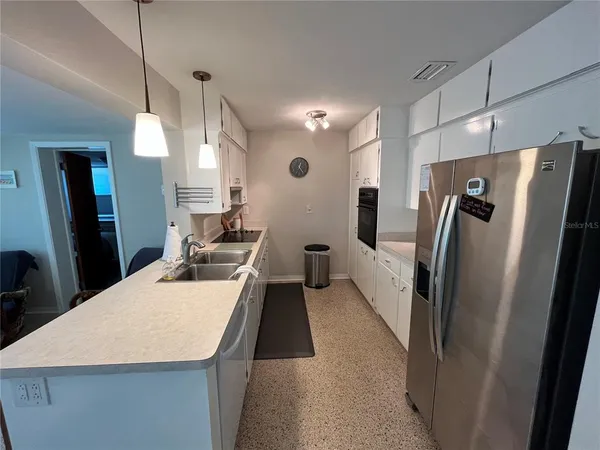 a kitchen with stainless steel appliances a refrigerator a sink a stove a table and chairs