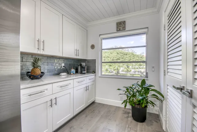 a kitchen with white cabinets and potted plant