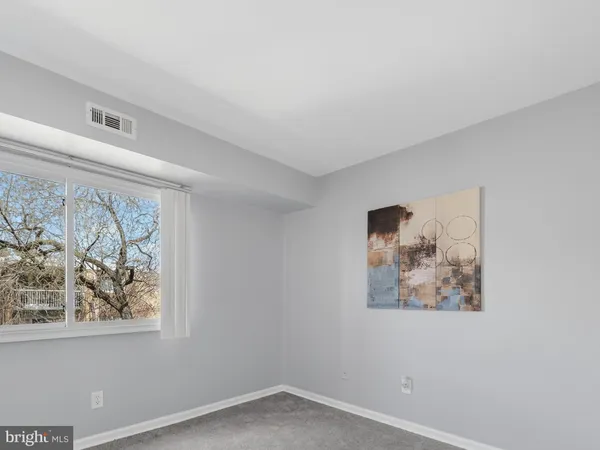 an empty room with painting on the wall and a window