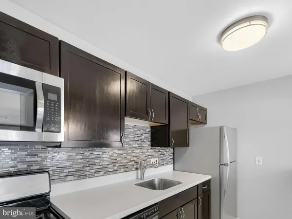 a kitchen with stainless steel appliances granite countertop a sink a stove a refrigerator a microwave a sink and cabinets