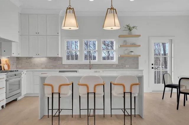 a kitchen with stainless steel appliances granite countertop a table chairs sink and cabinets