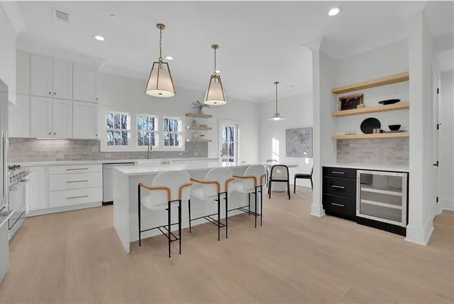 a kitchen with stainless steel appliances kitchen island granite countertop a stove a sink a dining table and chairs with wooden floor