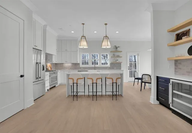 a kitchen with stainless steel appliances kitchen island granite countertop a table chairs sink and cabinets