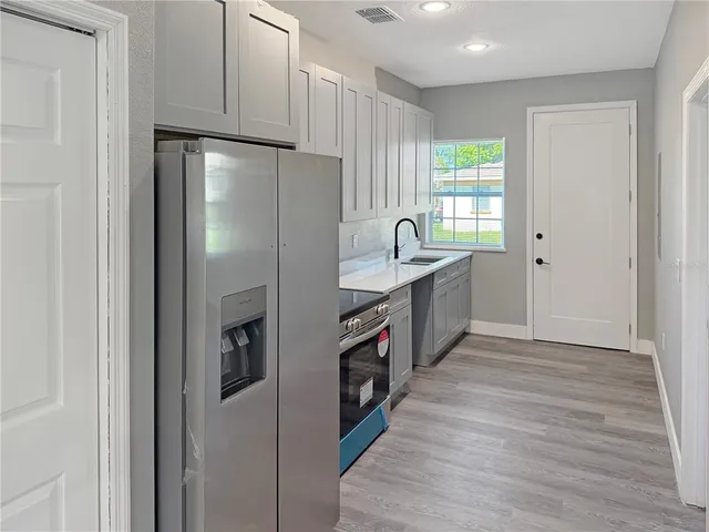 a kitchen with stainless steel appliances granite countertop a refrigerator a sink and a stove with wooden floors