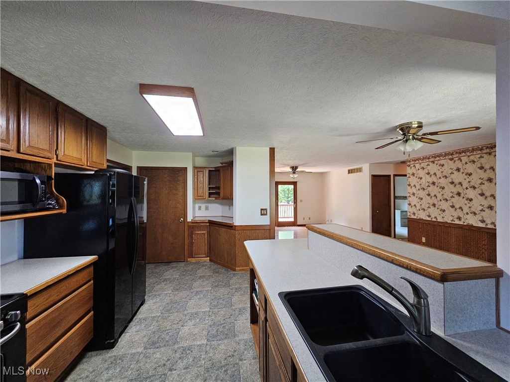 24192 Quarry Road Wellington, OH 44090 - Photo 13 of 28 Kitchen featuring wooden walls, a textured ceiling, black appliances, sink, and ceiling fan