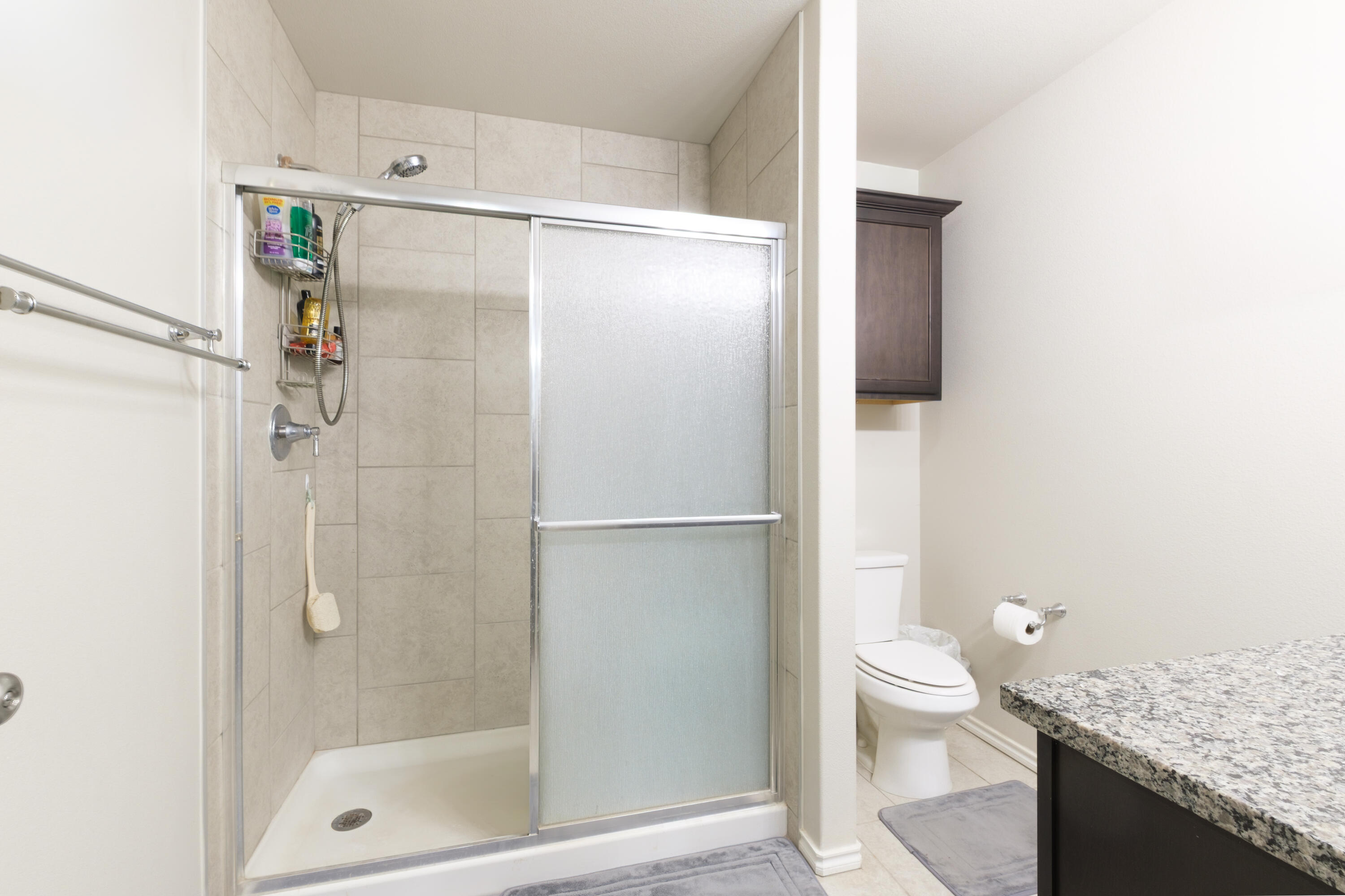 6821 39th Street Lubbock, TX 79407 - Photo 12 of 25 a bathroom with a granite countertop shower a toilet and sink