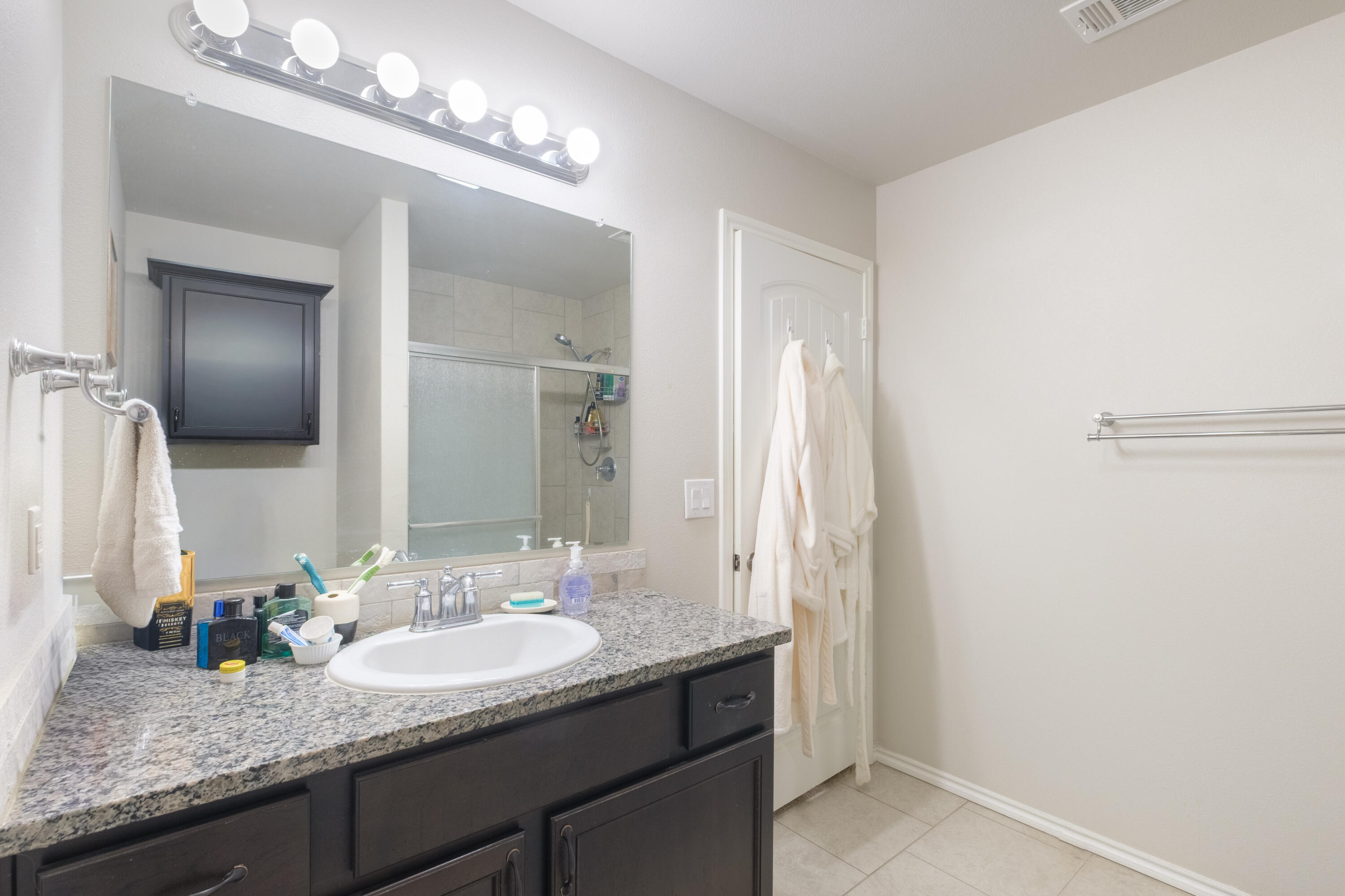 6821 39th Street Lubbock, TX 79407 - Photo 13 of 25 a bathroom with a granite countertop sink and a mirror