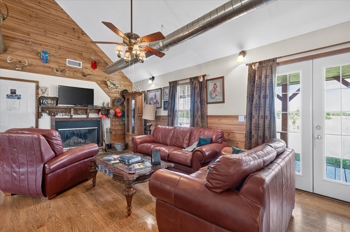 26115 4157th Road Nowata, OK 74048 - Photo 7 of 36 Vaulted wood-paneled ceiling, wood-finish flooring, built-in fireplace, exposed metal ductwork, and double glass-paneled doors