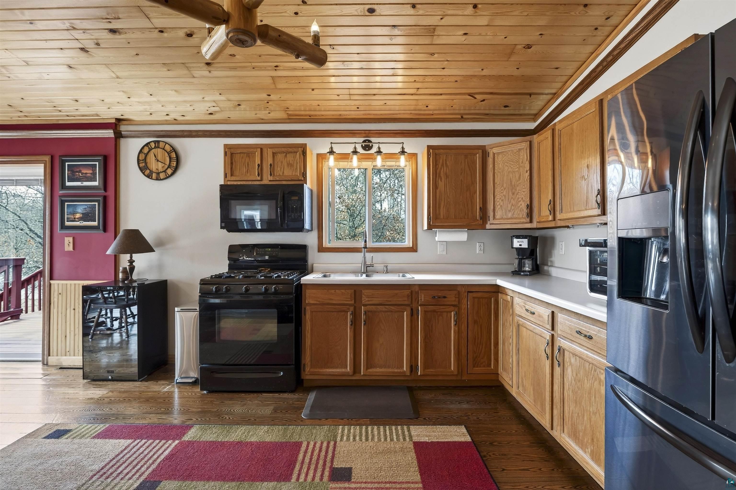 11702 East Mail Road Gordon, WI 54838 - Photo 38 of 49 Kitchen featuring black appliances, wood finish cabinets, wooden ceiling, light countertops, and ceiling fan