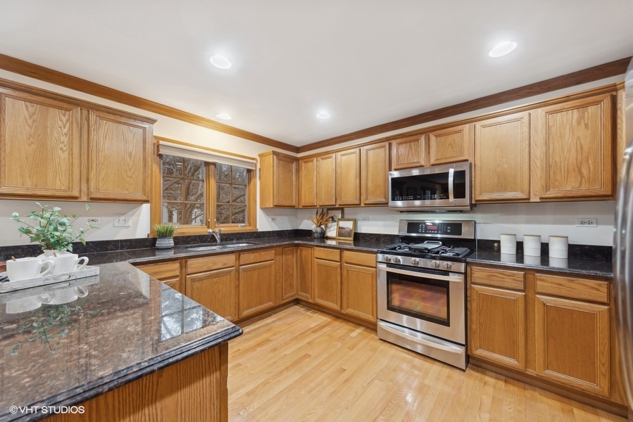 1114 Taft Avenue Wheaton, IL 60189 - Photo 4 of 24 a kitchen with stainless steel appliances granite countertop a stove top oven a sink dishwasher a microwave oven and a refrigerator with wooden floor