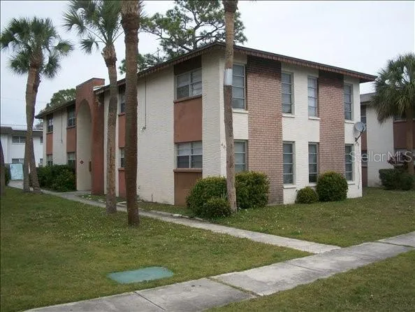 a brick house with a yard plants and large trees