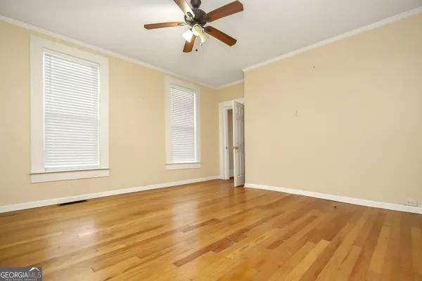 a view of an empty room with wooden floor and a window