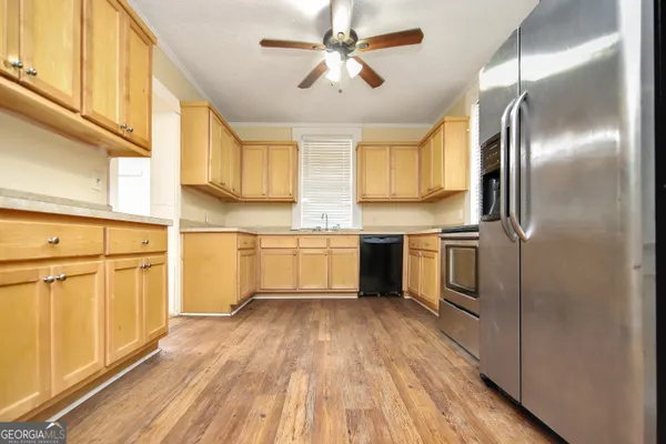 a kitchen with cabinets wooden floor and stainless steel appliances