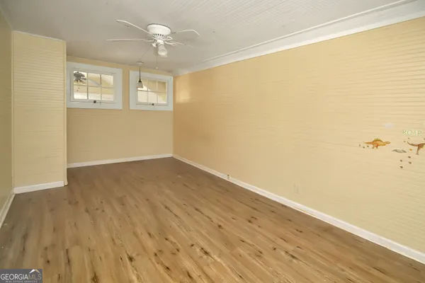 an empty room with wooden floor and windows