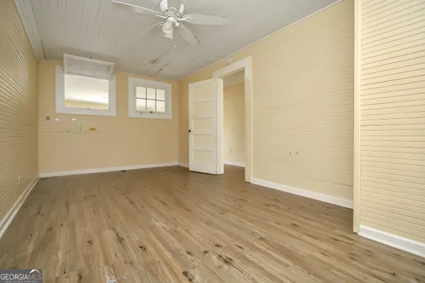 a view of an empty room with wooden floor and a window