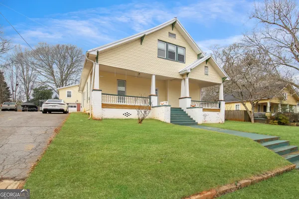 a view of a white house in front of a big yard with large trees