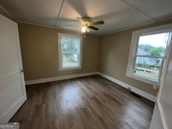 a view of an empty room with wooden floor and a window