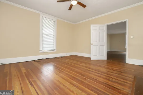an empty room with wooden floor chandelier fan and windows