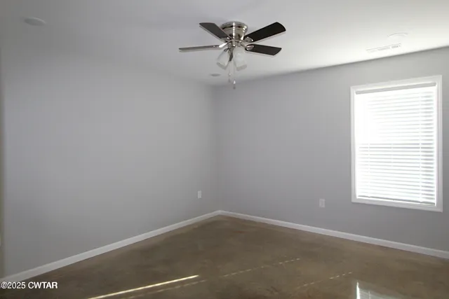 an empty room with a window and a fan