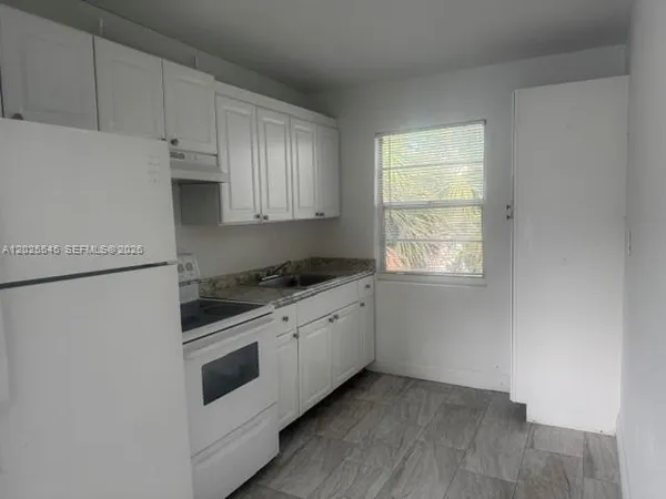 a kitchen with granite countertop white cabinets and white appliances