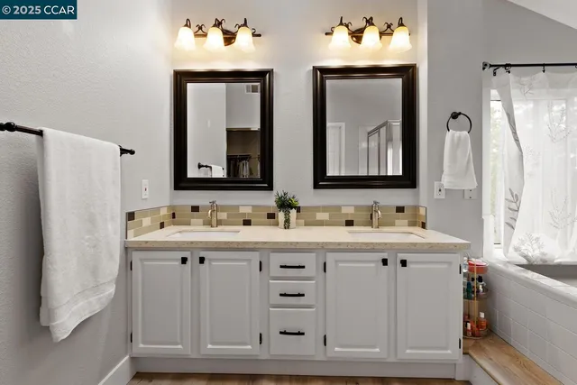 a spacious bathroom with double vanity a mirror a bathtub and shower
